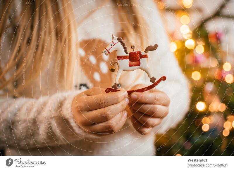 Decorating the christmas tree, girl holding an ornamental metal rocking horse human human being human beings humans person persons caucasian appearance