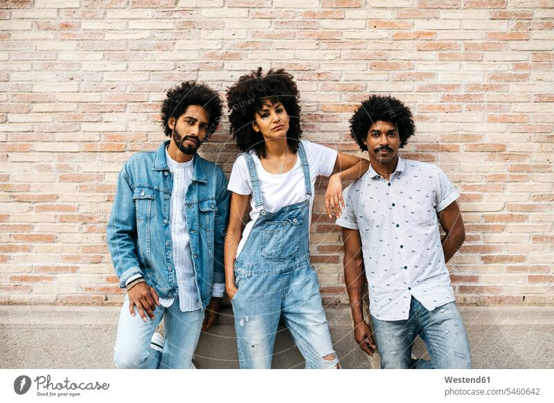 Portrait of three friends wearing denim standing in front of brick wall portrait portraits friendship young man young men mid adult women mid adult woman