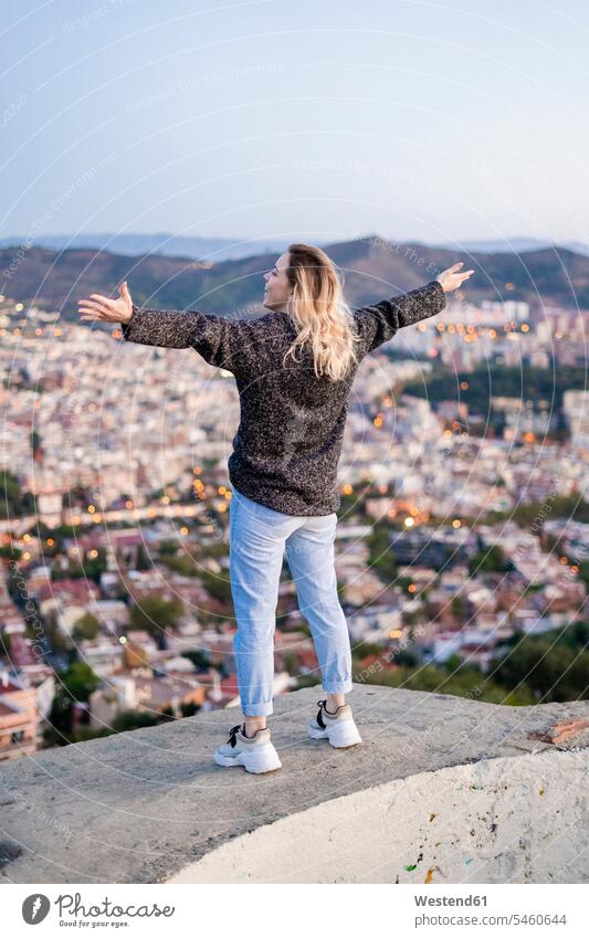 Rear view of carefree young woman standing above the city at sunrise, Barcelona, Spain human human being human beings humans person persons caucasian appearance
