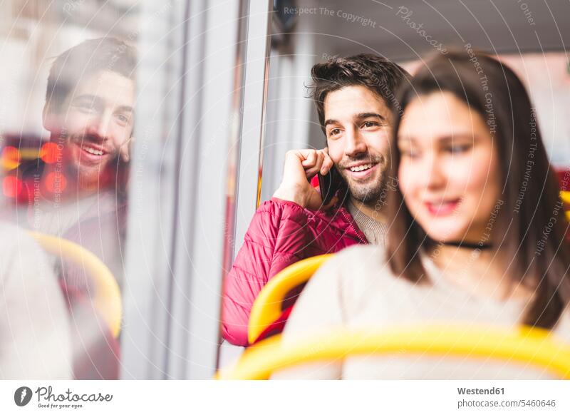 UK, London, portrait of smiling young man on the phone in a bus call telephoning On The Telephone calling smile portraits men males busses telephone call