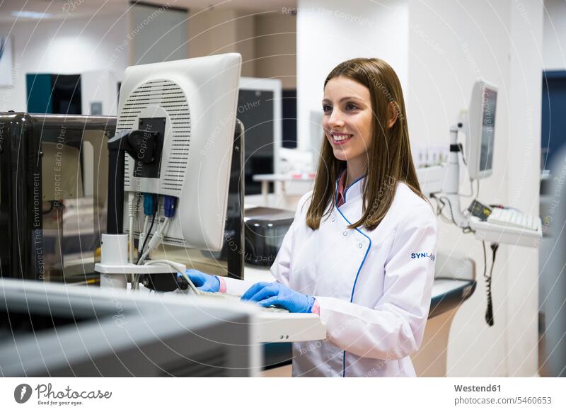 Young woman in white apparel using sample analyzer while working in research lab human human being human beings humans person persons caucasian appearance