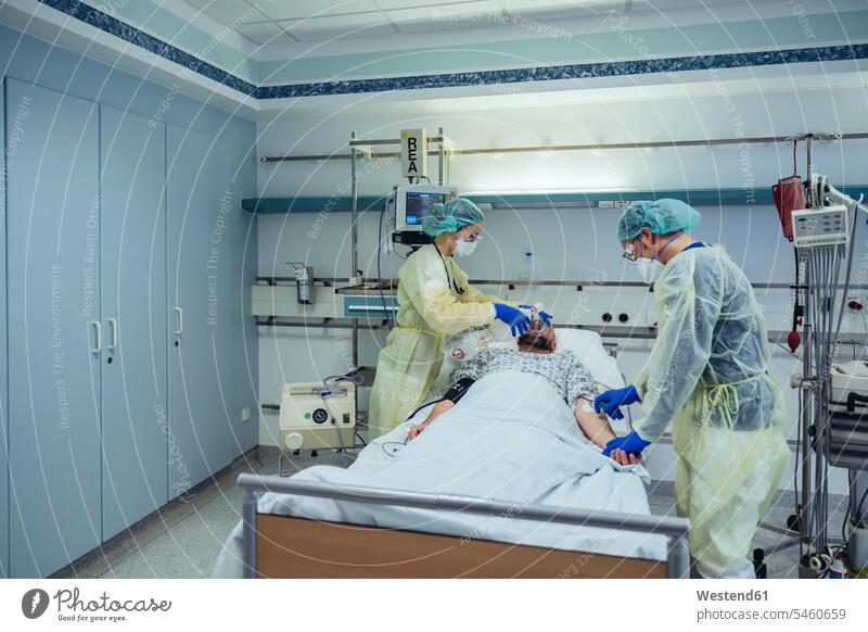 Doctors caring for patient in emergency care unit of a hospital changing breathing from oxygen mask to bag valve mask colleague health healthcare