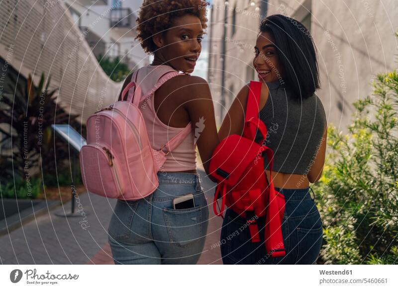 USA, Florida, Miami Beach, rear view of two happy female friends walking in the city town cities towns going happiness outdoors outdoor shots location shot