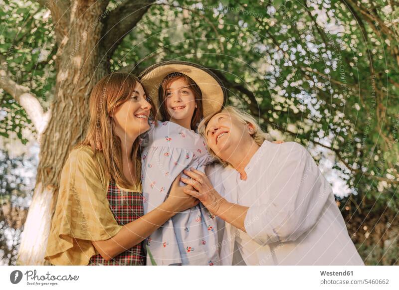 Happy family embracing girl wearing hat against tree in yard color image colour image Spain leisure activity leisure activities free time leisure time