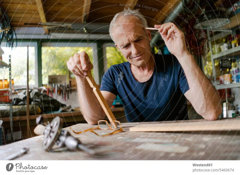 Mature man at workbench in his workshop thinking crafts hand work handcraft handicraft handwork manual labour manual work work shop work shops workshops human