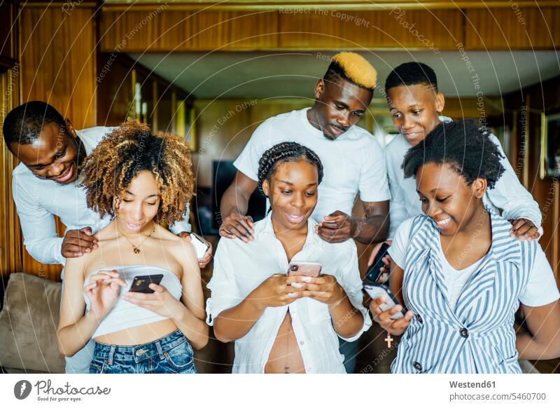 Family and friends using cell phones at home mate telecommunication telephone telephones Cellphone mobile mobile phones mobiles smile delight enjoyment Pleasant