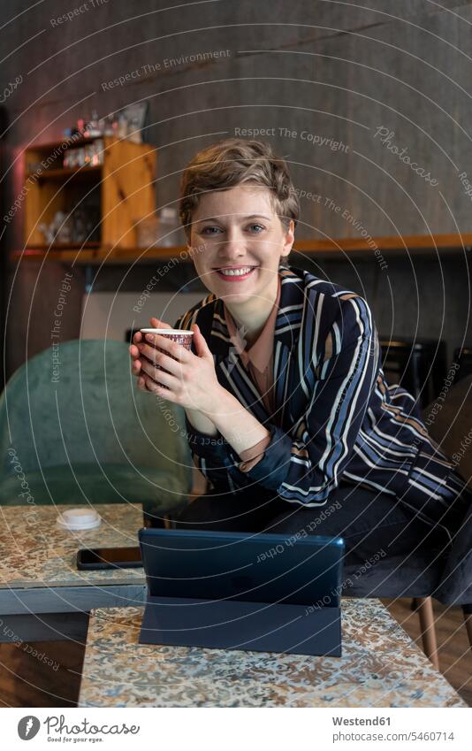 Portrait of smiling freelancer sitting in a coffee shop with digital tablet and smartphone business life business world business person businesspeople