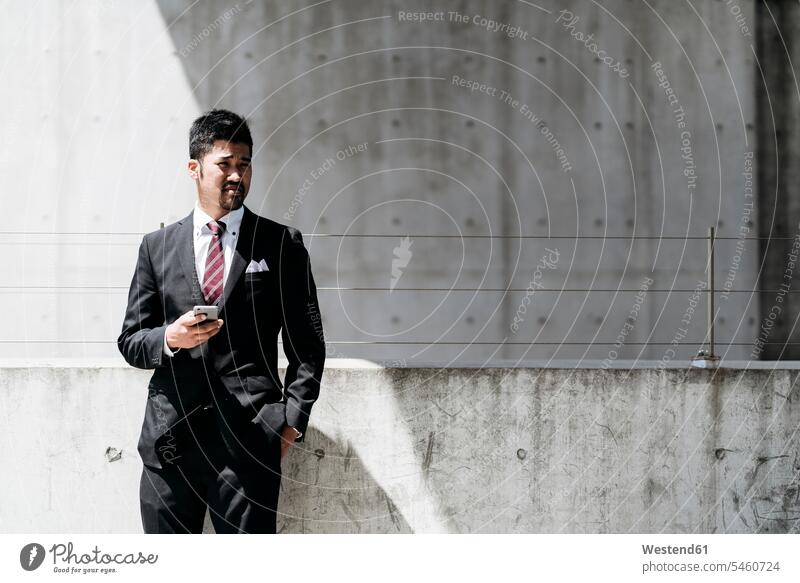 Young businessman standing at concrete wall in the city human human being human beings humans person persons Asian Asians Japanese 1 one person only