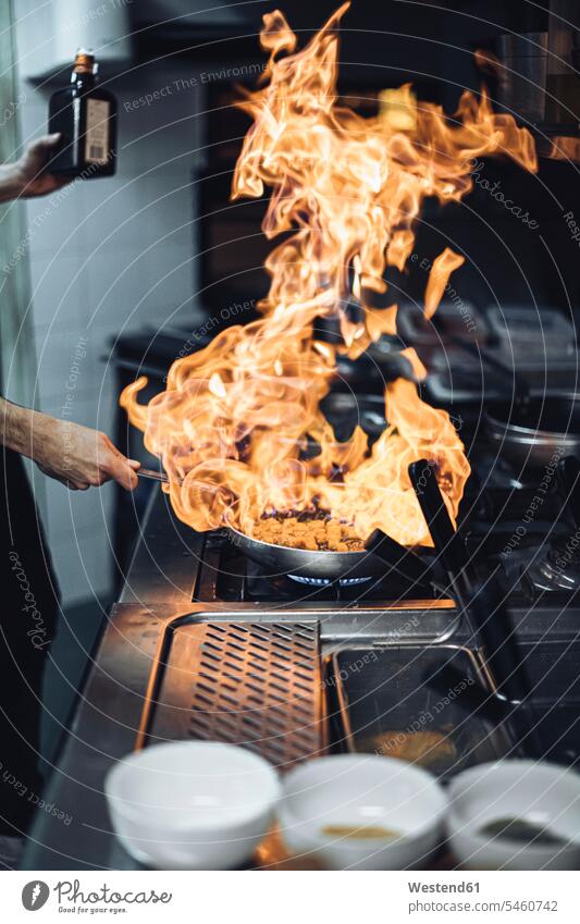 Chef preparing a flambe dish at gas stove in restaurant kitchen Occupation Work job jobs profession professional occupation Chefs cook cooks devices Cookers