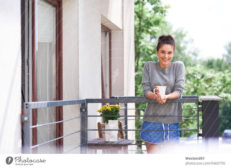 Young woman drinking morning coffee on the balcony standing young women young woman in the morning balconies Coffee females Adults grown-ups grownups adult