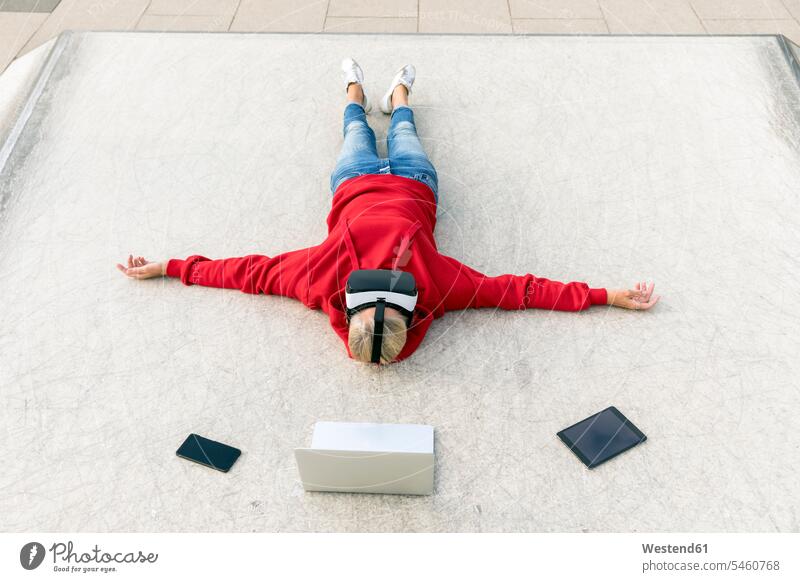 Senior woman lying on the ground wearing VR glasses next to mobile devices specs Eye Glasses spectacles Eyeglasses laying down lie lying down land floor virtual