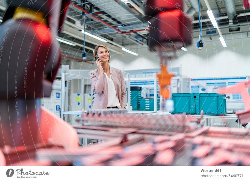 Businesswoman on cell phone in a modern factory hall human human being human beings humans person persons caucasian appearance caucasian ethnicity european 1