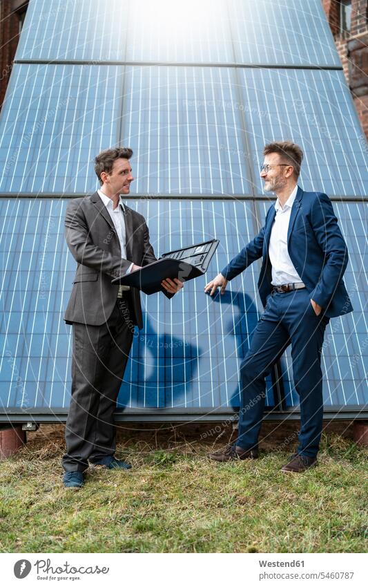 Two businessmen talking at solar panels speaking solar cell solar cells photovoltaics solar energy solar power Solar renewable energy alternative energy ecology