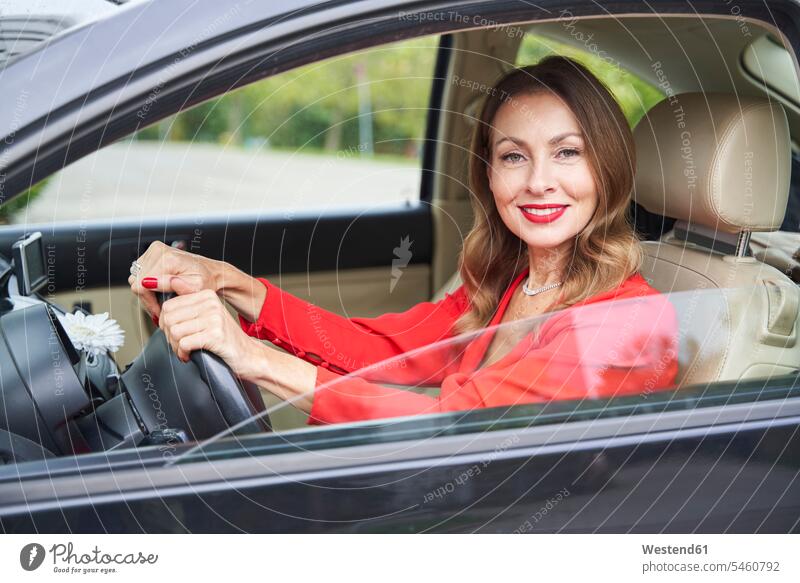 Portrait of smiling mature woman in car dresses motor vehicles road vehicle road vehicles Auto automobile Automobiles cars motorcar motorcars steering wheels