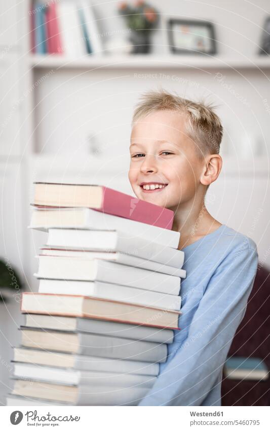 Portrait of smiling blond boy carrying stack of books learn read smile delight enjoyment Pleasant pleasure happy Contented Emotion pleased at home free time