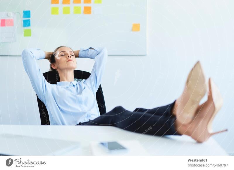 Young businesswoman relaxing in office reclining with feet on desk human human being human beings humans person persons caucasian appearance caucasian ethnicity