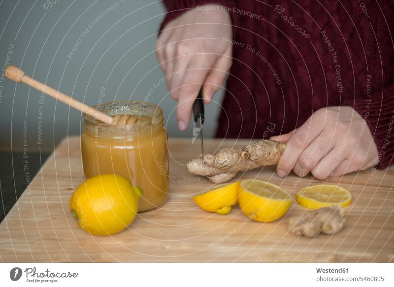 Hands of young woman cutting ginger root on wooden board ginger roots hand human hand hands human hands wooden boards wooden panel wooden panels females women