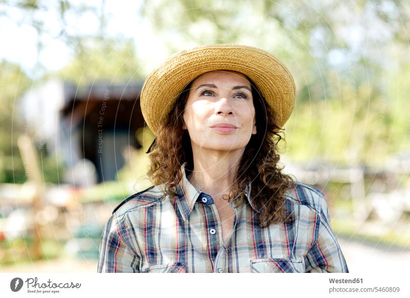 Thoughtful mature female farmer looking up while standing at community garden color image colour image Germany outdoors location shots outdoor shot