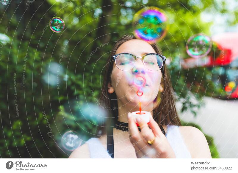 Teenage girl blowing soap bubbles outdoors Teenage Girls female teenagers Teenager Teens people persons human being humans human beings playing copy space