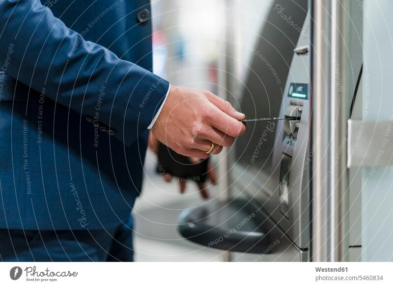 Close-up of businessman withdrawing money at an ATM color image colour image outdoors location shots outdoor shot outdoor shots day daylight shot daylight shots