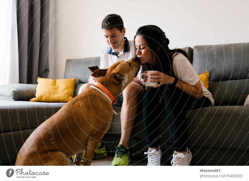 Woman kissing pet dog while sitting on sofa at home color image colour image indoors indoor shot indoor shots interior interior view Interiors day daylight shot