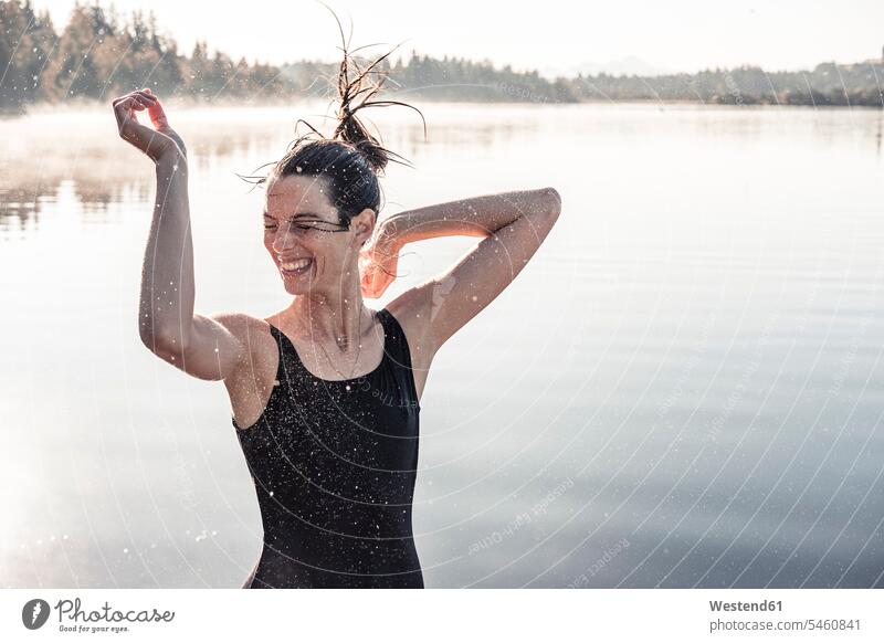 Cheerful woman wearing black swimsuit at a lake at morning mist swim wear bathing costume bathing costumes bathing suit bathing suits Swimming Costume