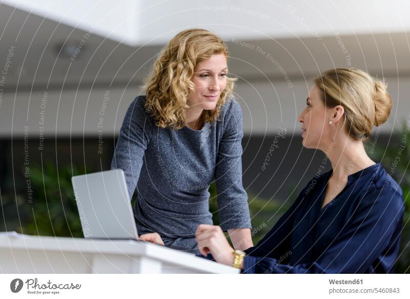 Two women talking at desk in office colleague associate associates partner partners partnerships Occupation Work job jobs profession professional occupation
