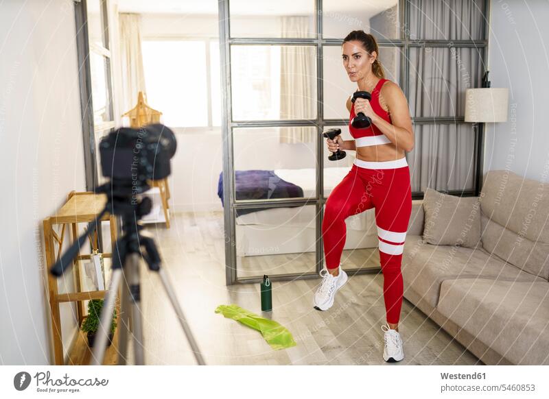 Woman exercising with dumbbell in front of camera at home color image colour image indoors indoor shot indoor shots interior interior view Interiors day