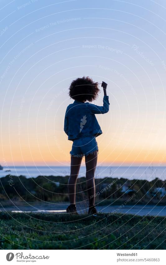 Rear view of young woman with hand in hair standing on a viewpoint at sunset, Ibiza in the evening Late Evening Contented Emotion pleased free Liberty free time