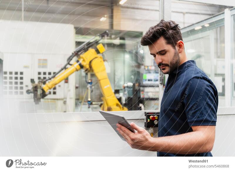 Male factory worker using digital tablet while standing in manufacturing industry color image colour image indoors indoor shot indoor shots interior