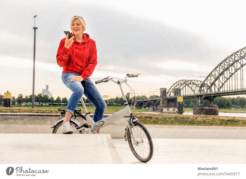 Senior woman with city bike using cell phone bicycle bikes bicycles confidence confident mobile phone mobiles mobile phones Cellphone cell phones females women