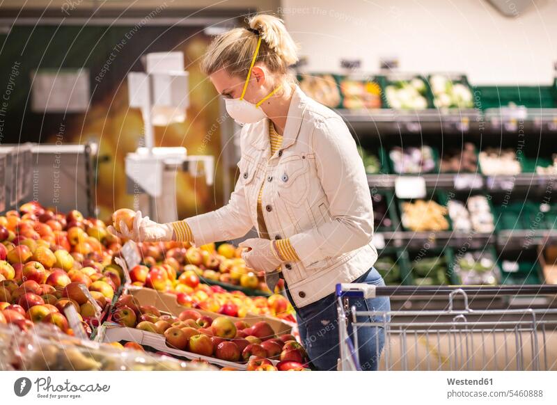 Teenage girl wearing protectice mask and gloves choosing apples at supermarket human human being human beings humans person persons caucasian appearance