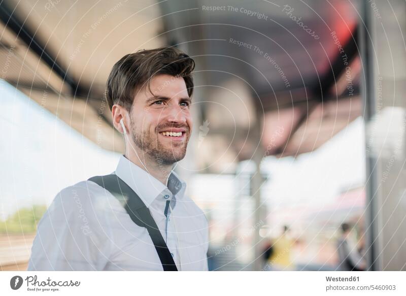 Portrait of smiling businessman on station platform with earphones smile Businessman Business man Businessmen Business men portrait portraits Railroad Platform