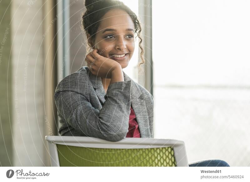 Smiling young businesswoman sitting on a chair in office Occupation Work job jobs profession professional occupation human human being human beings humans