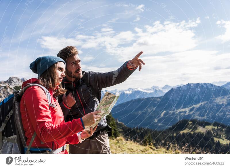 Austria, Tyrol, young couple with map in mountainscape looking around mountain range mountain ranges maps hiking hike twosomes partnership couples looking round