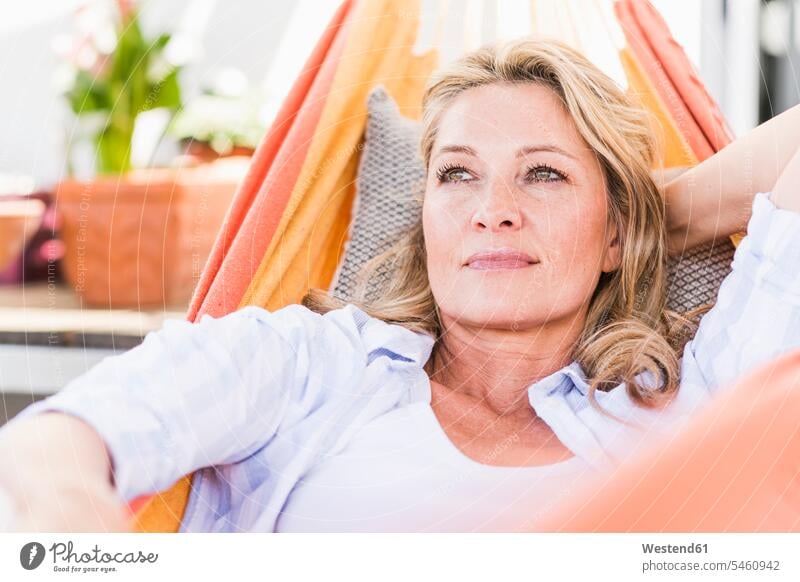 Portrait of pensive mature woman relaxing in hammock cushions hammocks contemplative pensively Reflective thoughtful laying down lie lying down at home