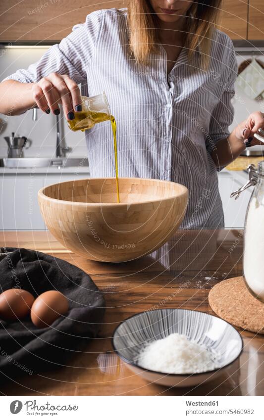 Woman pouring oil in wooden bowl preparing Food Preparation preparing food Mixing Bowl preparation prepare baking bake oils Bowls foods food and drink Nutrition