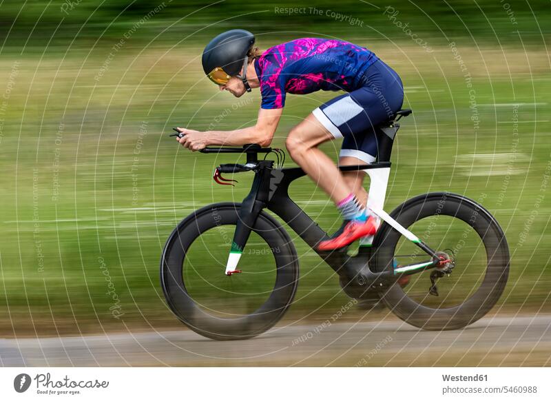 Triathlete riding bicycle on country road, Germany human human being human beings humans person persons caucasian appearance caucasian ethnicity european 1