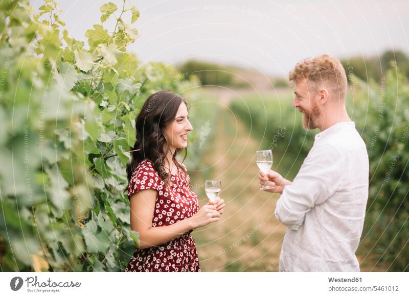 Couple drinking white wine in the vineyards smile speak speaking talk delight enjoyment Pleasant pleasure happy stand country countryside free time leisure time