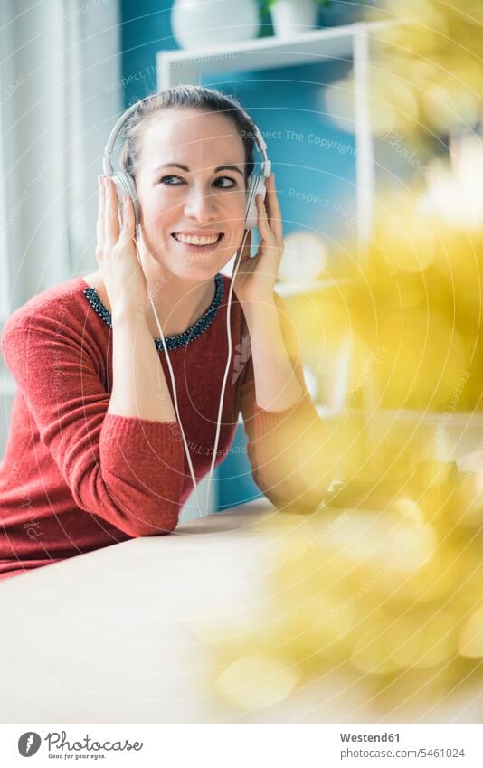 Portrait of happy woman with listening music with headphones Table Tables headset hearing females women portrait portraits happiness Adults grown-ups grownups