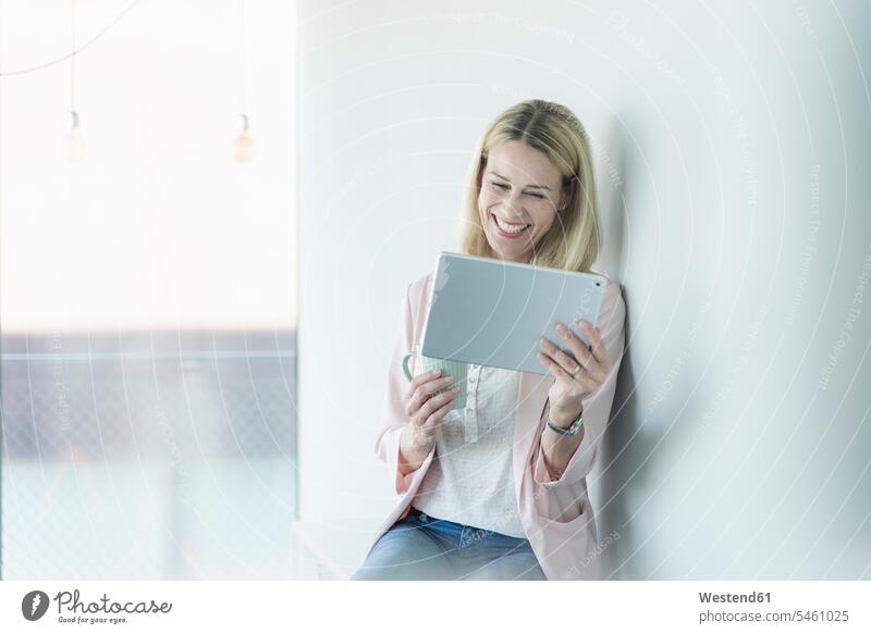 Happy businesswoman leaning against a wall using tablet Germany toothy smile big smile open smile laughing wireless Wireless Connection Wireless Technology