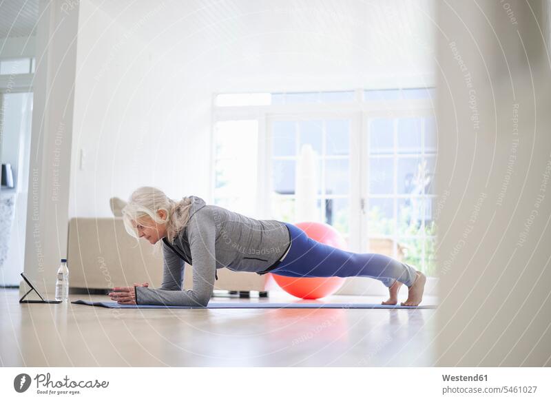 Active senior woman practicing plank position on mat at home color image colour image Denmark Scandinavia Scandinavian Peninsula indoors indoor shot