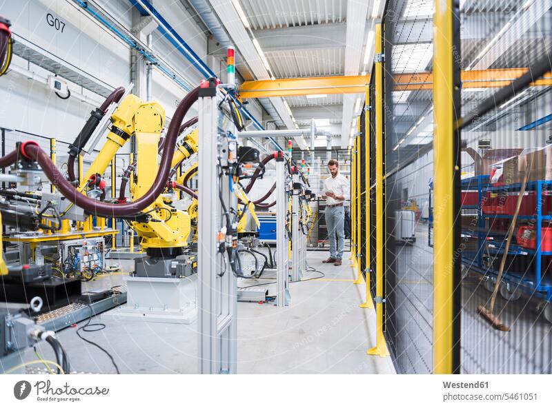 Full length of confident engineer working at automated robotic factory color image colour image Germany indoors indoor shot indoor shots interior interior view
