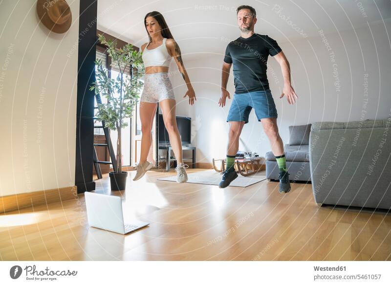 Couple jumping while exercising on hardwood floor at home color image colour image Spain indoors indoor shot indoor shots interior interior view Interiors