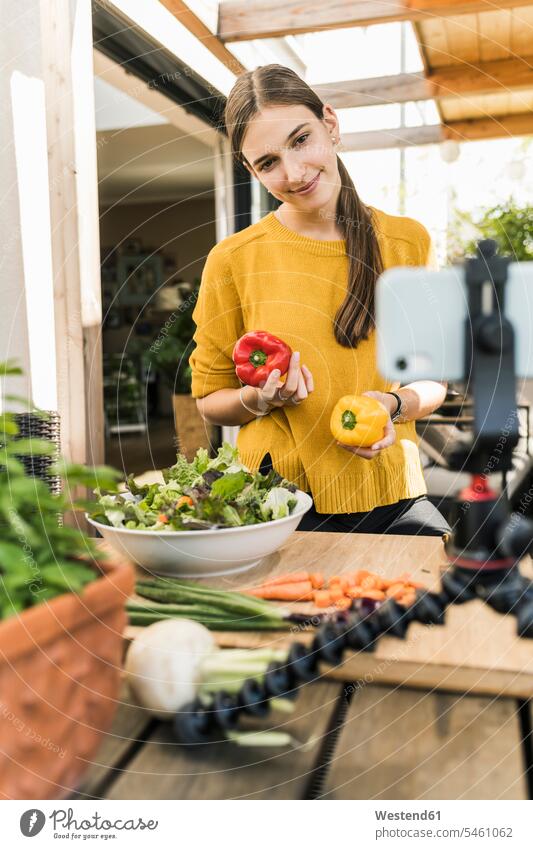 Smiling woman filming with mobile phone while preparing food at home color image colour image Germany casual clothing casual wear leisure wear casual clothes