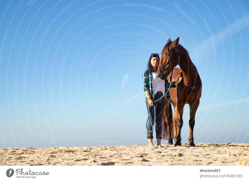 Woman with horse standing in sand woman females women equus caballus horses sandy Adults grown-ups grownups adult people persons human being humans human beings