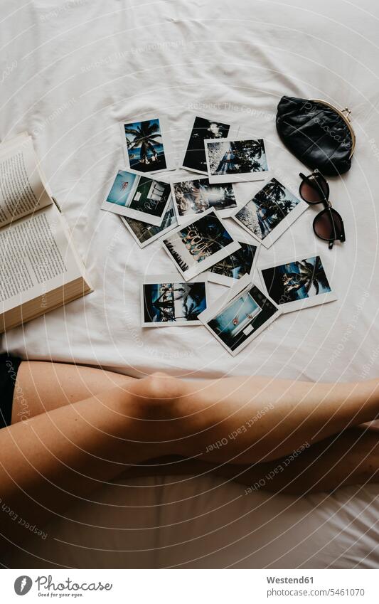 Legs of young woman in bed with book and polaroid pictures purses Memory memories convenience amenities convenient amenity comfort comfortable low section