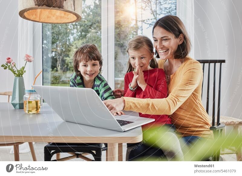 Happy mother with two children using laptop at home mommy mothers ma mummy mama Laptop Computers laptops notebook happiness happy parents family families people