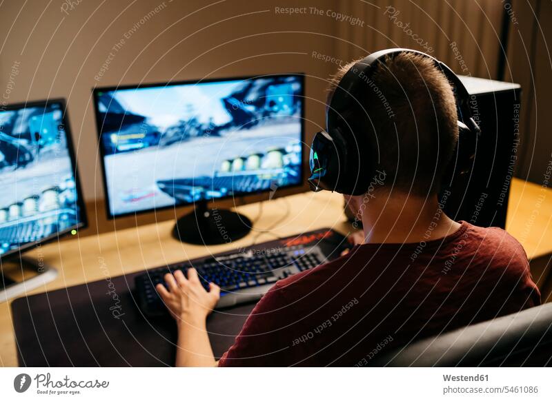 Young man playing video games with computer at desk color image colour image indoors indoor shot indoor shots interior interior view Interiors using computer