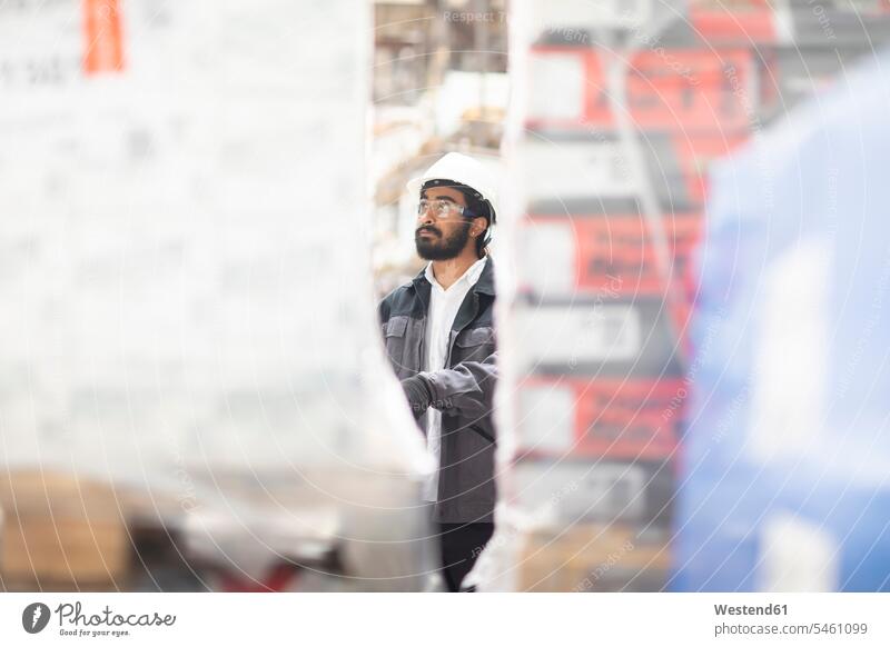 Young man wearing hard hat working in a warehouse human human being human beings humans person persons Indian 1 one person only only one person adult grown-up